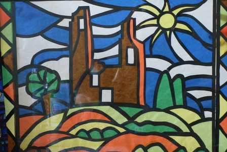 : Photo d’une œuvre inspirée de la technique du vitrail. Les tours de l’abbaye de Mont-Saint-Éloi sont représentés au milieu de la campagne en haut d’une colline. En arrière-plan, le soleil brille et le ciel bleu est parsemé de nuage.