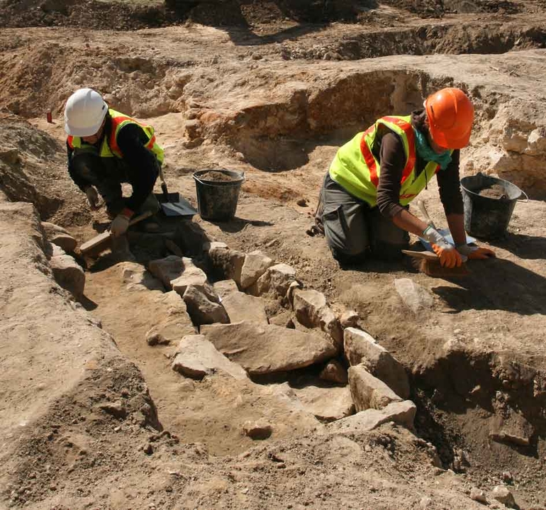 Des archéologues dégagent une tombe à coffrage en dalles de grès. L'architecture funéraire caractérise souvent des pratiques propres à chaque époque.