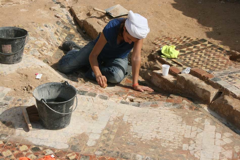 Une archéologue nettoie les pavages de la crypte principale à l'eau déminéralisée.